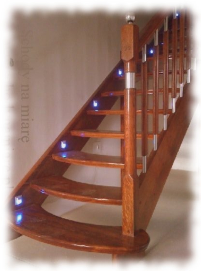 Klatka schodowa z drewna o ciemnym odcieniu, z małymi niebieskimi lampkami LED wbudowanymi w stopnie i balustradą z metalowymi elementami.